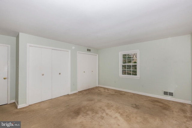 unfurnished bedroom featuring carpet and multiple closets