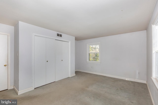 unfurnished bedroom with light carpet and a closet