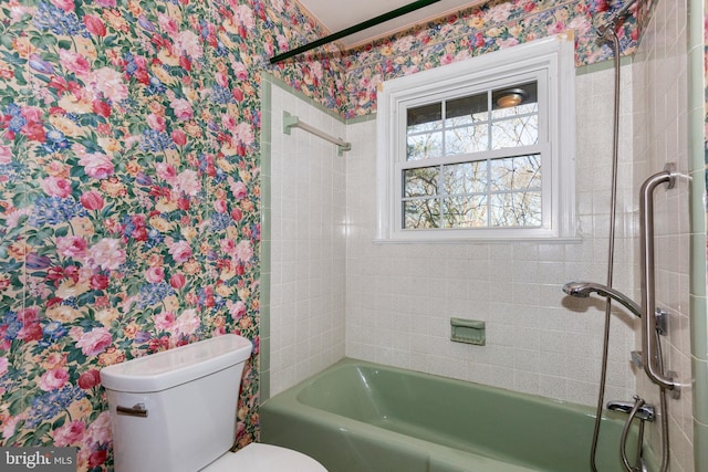 bathroom with tiled shower / bath combo and toilet