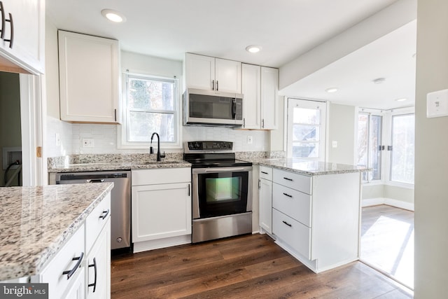 kitchen with sink, appliances with stainless steel finishes, tasteful backsplash, dark hardwood / wood-style flooring, and white cabinetry