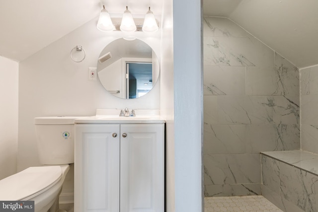 bathroom featuring tiled shower, vanity, vaulted ceiling, and toilet