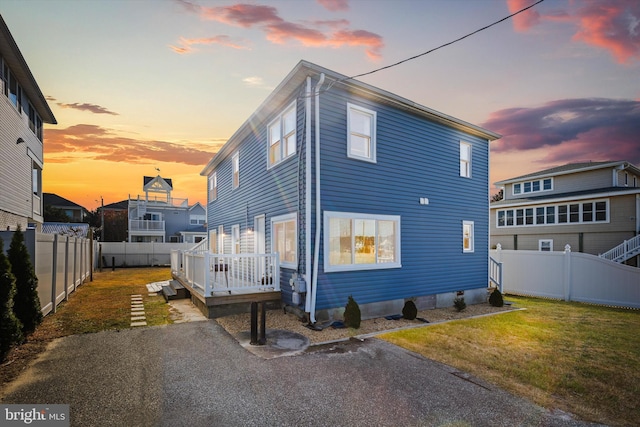 back house at dusk with a deck and a lawn