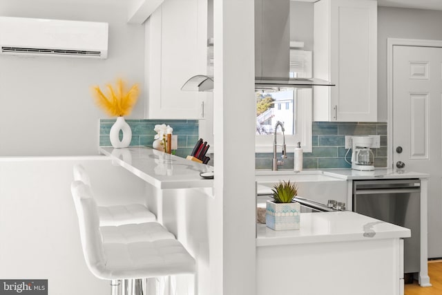 kitchen featuring decorative backsplash, stainless steel dishwasher, a wall mounted AC, sink, and white cabinets