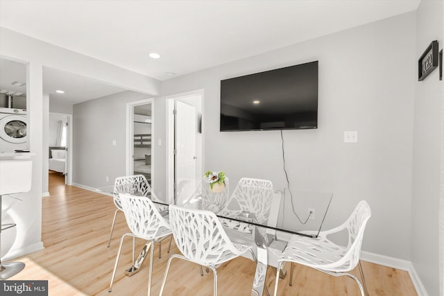 dining space with hardwood / wood-style floors and stacked washer and dryer