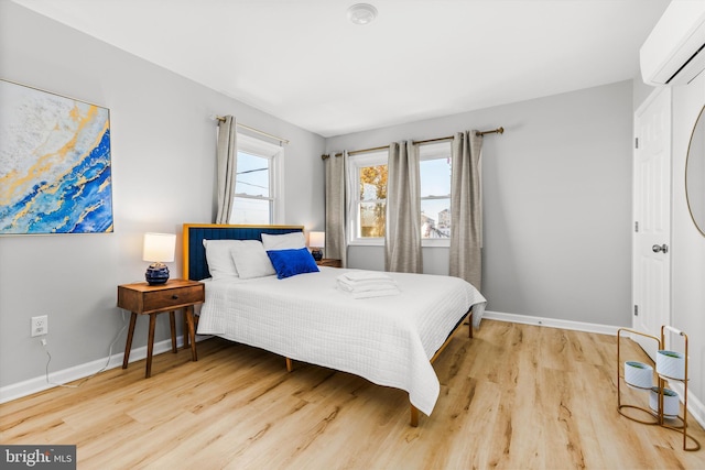 bedroom featuring a wall mounted AC and light hardwood / wood-style flooring