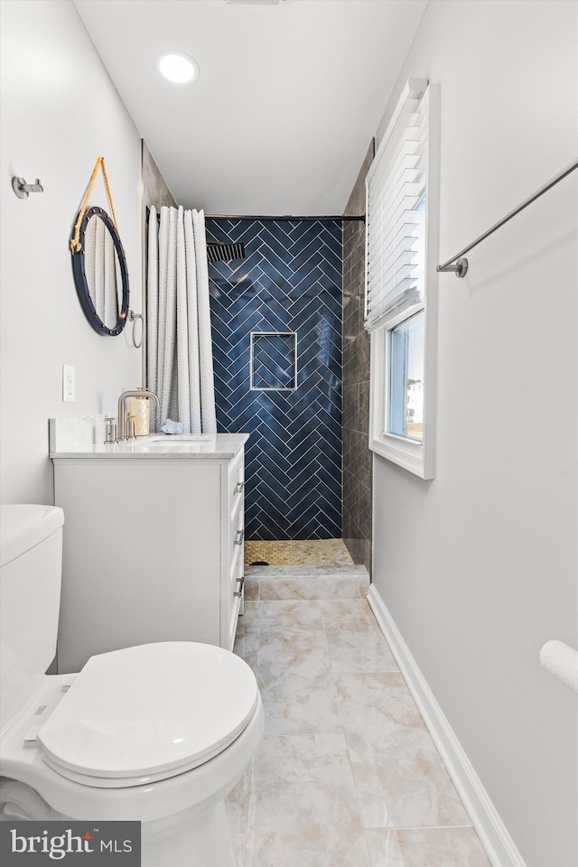 bathroom featuring tiled shower, vanity, and toilet