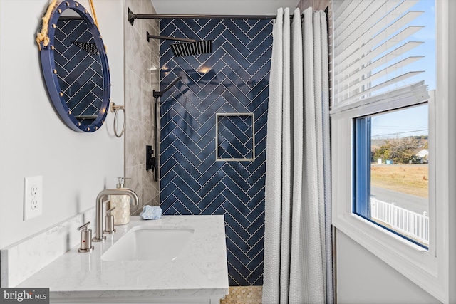 bathroom featuring tiled shower and vanity