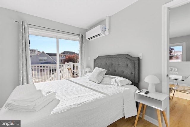 bedroom with hardwood / wood-style flooring and a wall unit AC