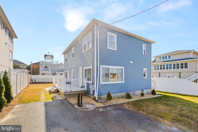 rear view of house featuring a wooden deck and a yard