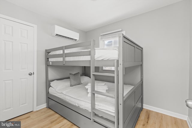 bedroom with light wood-type flooring and a wall unit AC