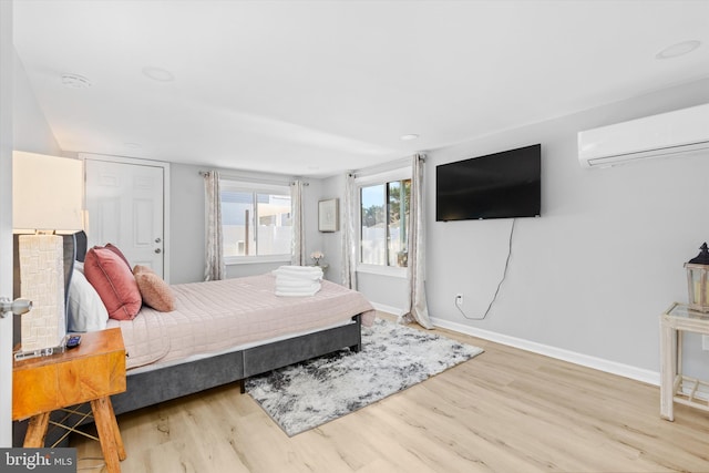 bedroom featuring hardwood / wood-style flooring and a wall mounted AC