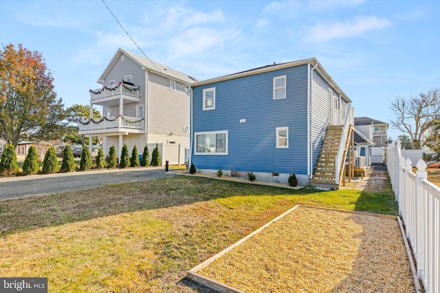 back of house featuring a balcony and a lawn