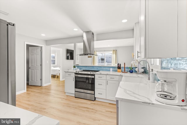 kitchen featuring light stone countertops, island range hood, stainless steel electric stove, a barn door, and white cabinetry