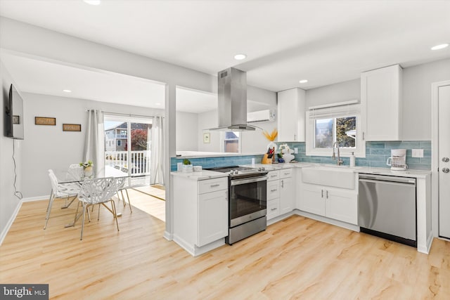 kitchen with white cabinets, island exhaust hood, stainless steel appliances, and a wealth of natural light