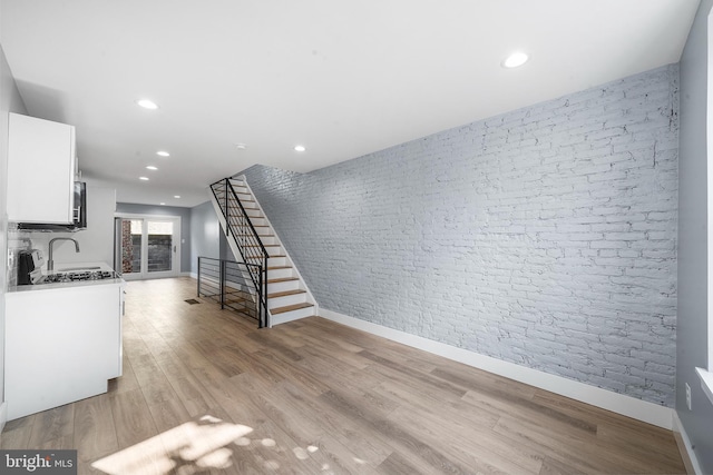 kitchen featuring light hardwood / wood-style flooring, white cabinetry, and brick wall