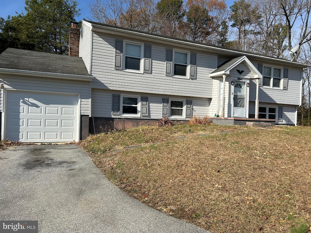 raised ranch featuring a front yard and a garage