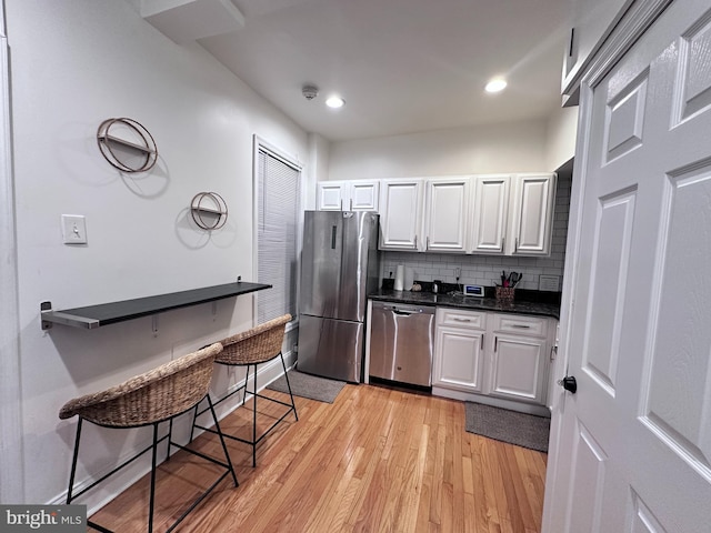 kitchen featuring decorative backsplash, light wood-type flooring, white cabinetry, and stainless steel appliances