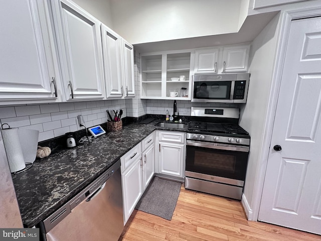 kitchen featuring sink, tasteful backsplash, appliances with stainless steel finishes, white cabinets, and light wood-type flooring