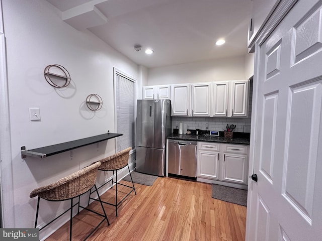 kitchen featuring backsplash, white cabinetry, light hardwood / wood-style floors, and appliances with stainless steel finishes