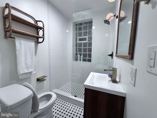 bathroom with a tile shower, tile patterned floors, vanity, and toilet