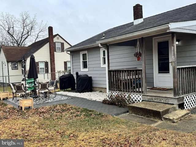 rear view of property featuring covered porch and a yard