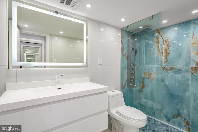 bathroom featuring vanity, toilet, tile walls, and a shower with shower door