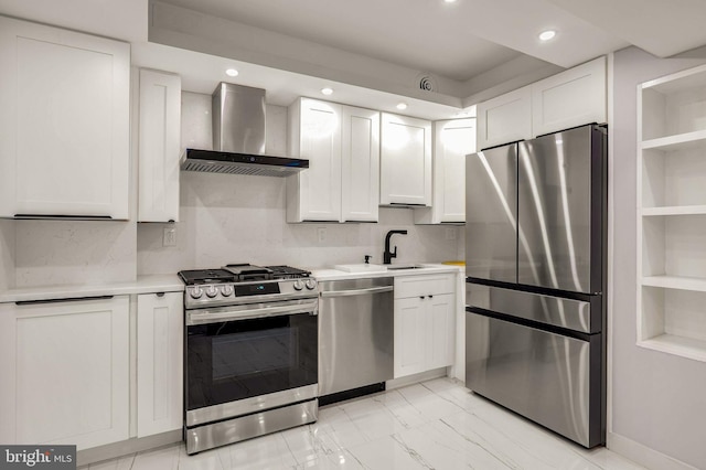 kitchen featuring backsplash, white cabinets, wall chimney range hood, sink, and appliances with stainless steel finishes