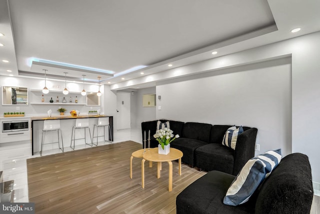 living room featuring a raised ceiling and light wood-type flooring