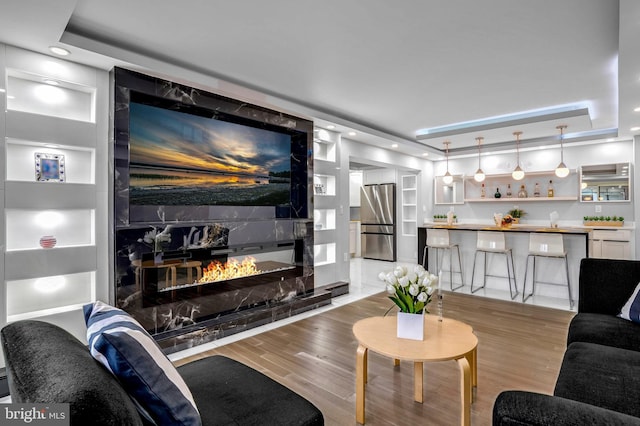 living room with hardwood / wood-style flooring, a raised ceiling, and a premium fireplace