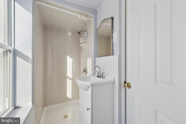 bathroom with tiled shower and vanity