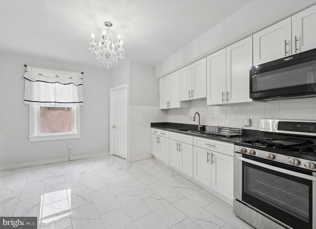 kitchen featuring stainless steel range with gas cooktop, sink, pendant lighting, a notable chandelier, and white cabinetry