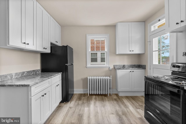 kitchen with black appliances, white cabinetry, radiator, and light hardwood / wood-style flooring