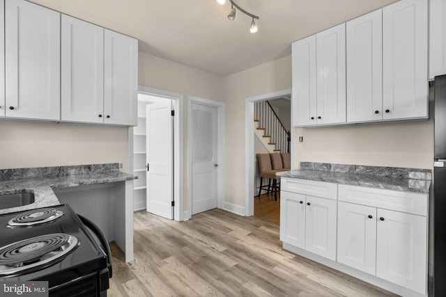 kitchen featuring electric range, white cabinets, light hardwood / wood-style floors, and stone countertops