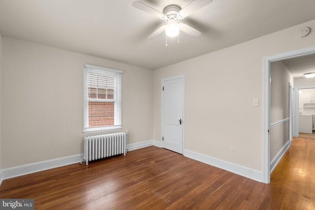 empty room featuring dark hardwood / wood-style flooring, ceiling fan, and radiator heating unit