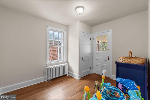 bedroom with radiator heating unit and hardwood / wood-style flooring