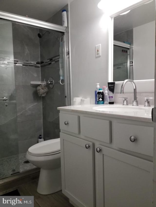 bathroom featuring wood-type flooring, vanity, toilet, and an enclosed shower