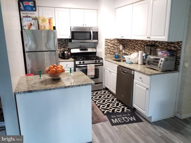 kitchen with white cabinetry, sink, light hardwood / wood-style floors, decorative backsplash, and appliances with stainless steel finishes