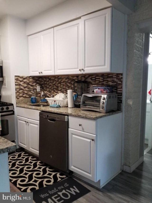 kitchen featuring appliances with stainless steel finishes, dark hardwood / wood-style flooring, backsplash, light stone counters, and white cabinetry