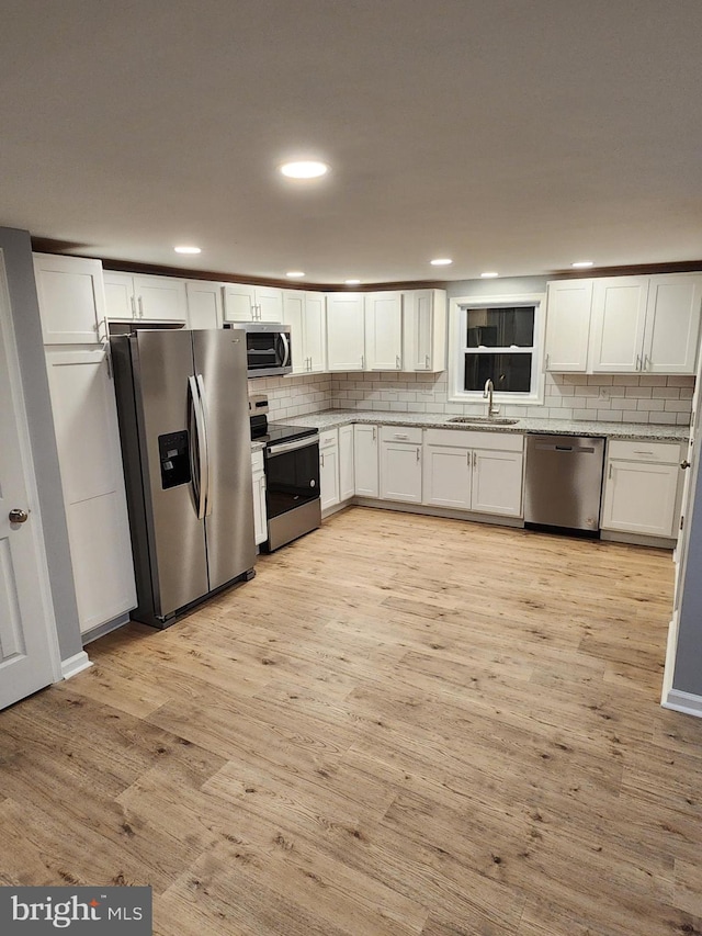 kitchen with white cabinetry, sink, light hardwood / wood-style flooring, backsplash, and appliances with stainless steel finishes