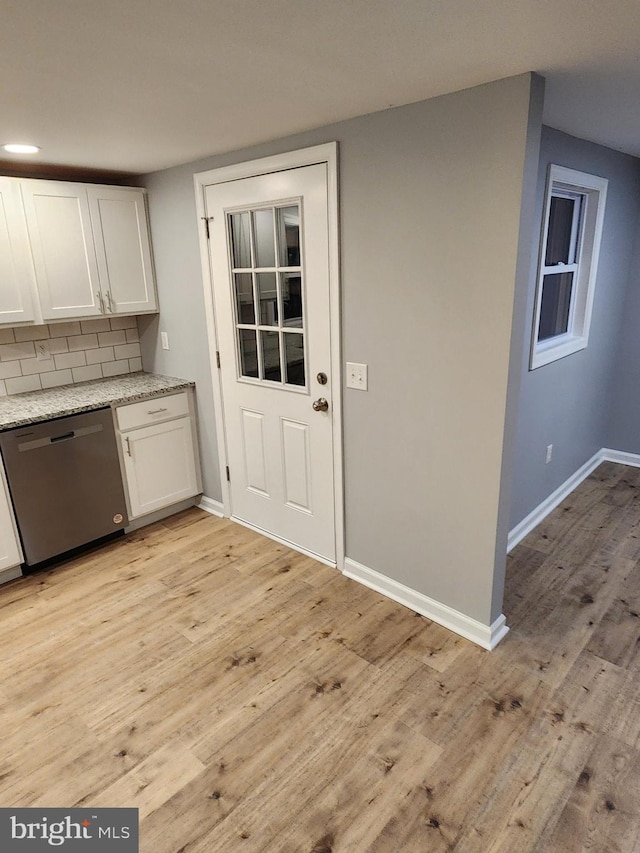 kitchen featuring white cabinetry, dishwasher, tasteful backsplash, light stone counters, and light wood-type flooring