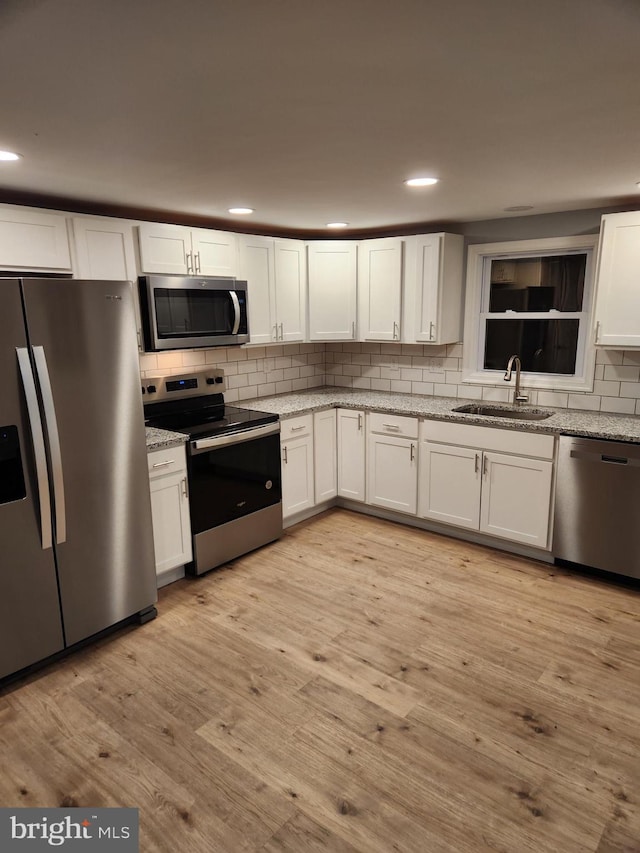 kitchen featuring white cabinetry, sink, stainless steel appliances, and light hardwood / wood-style floors