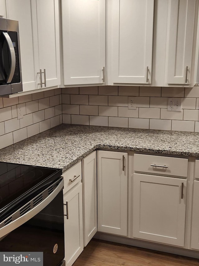 kitchen with tasteful backsplash, white cabinetry, and light stone counters