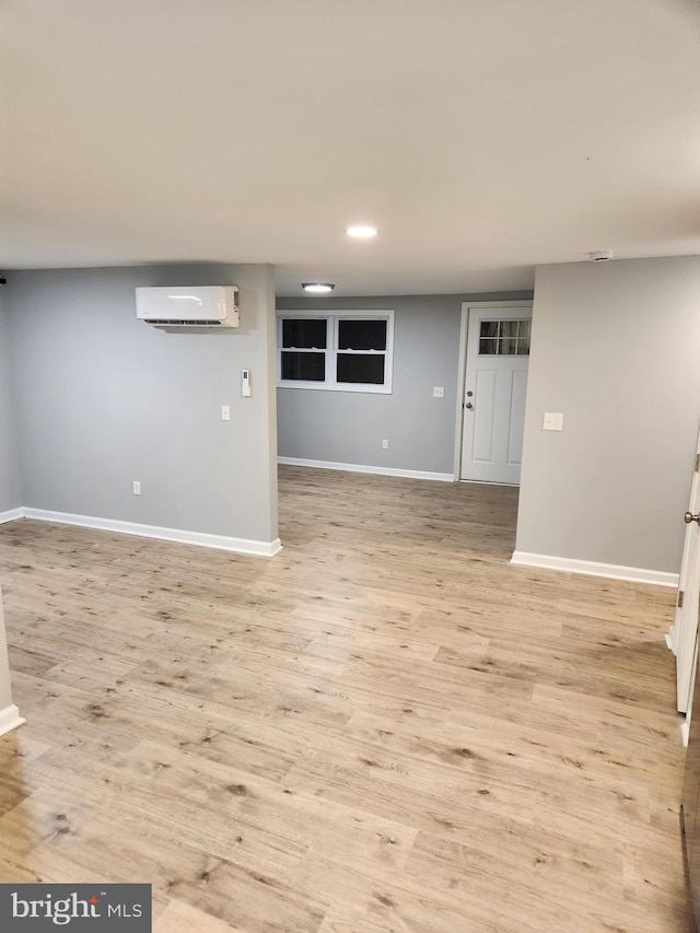 unfurnished living room featuring light hardwood / wood-style floors and an AC wall unit