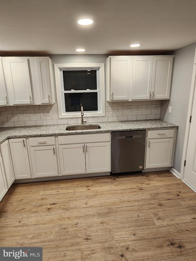 kitchen featuring sink, white cabinets, stainless steel dishwasher, and light hardwood / wood-style flooring