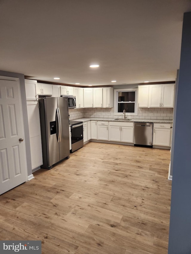 kitchen with white cabinets, light wood-type flooring, stainless steel appliances, and sink