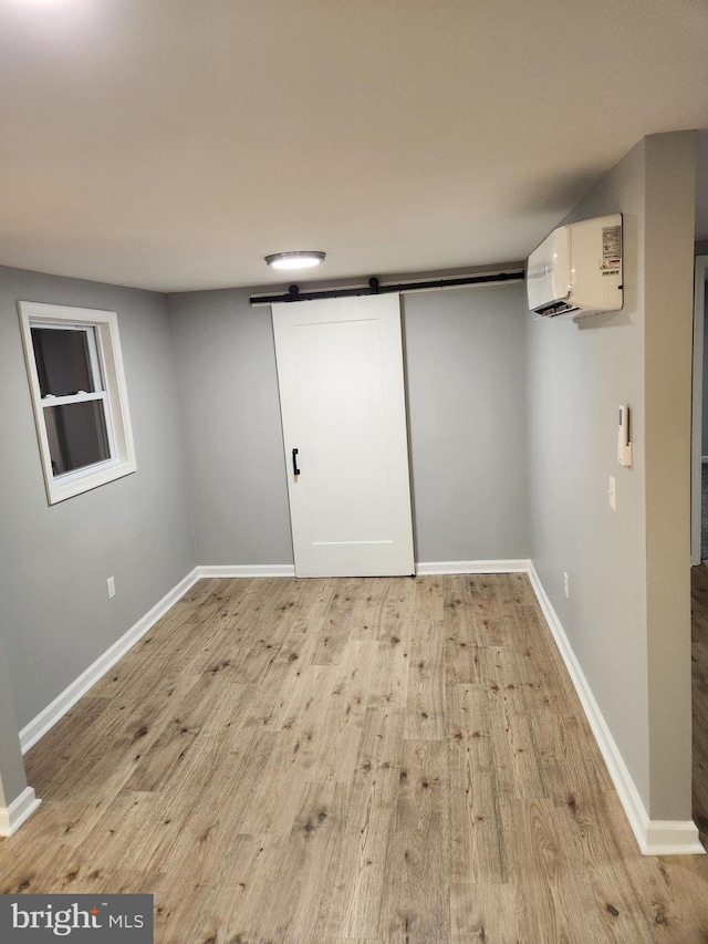 basement with an AC wall unit and light hardwood / wood-style floors