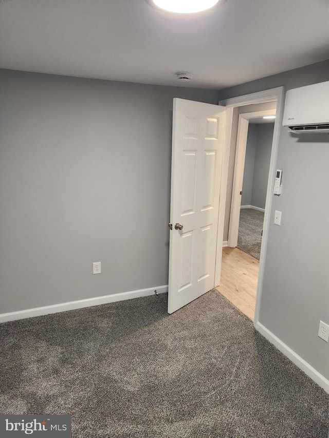 unfurnished room featuring a wall unit AC and carpet