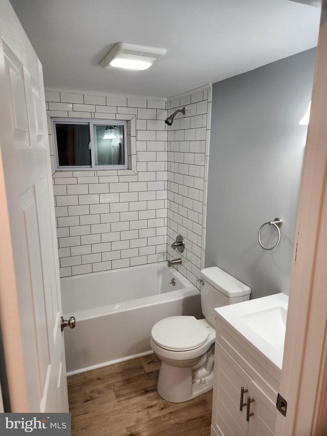 full bathroom with tiled shower / bath, hardwood / wood-style floors, vanity, and toilet