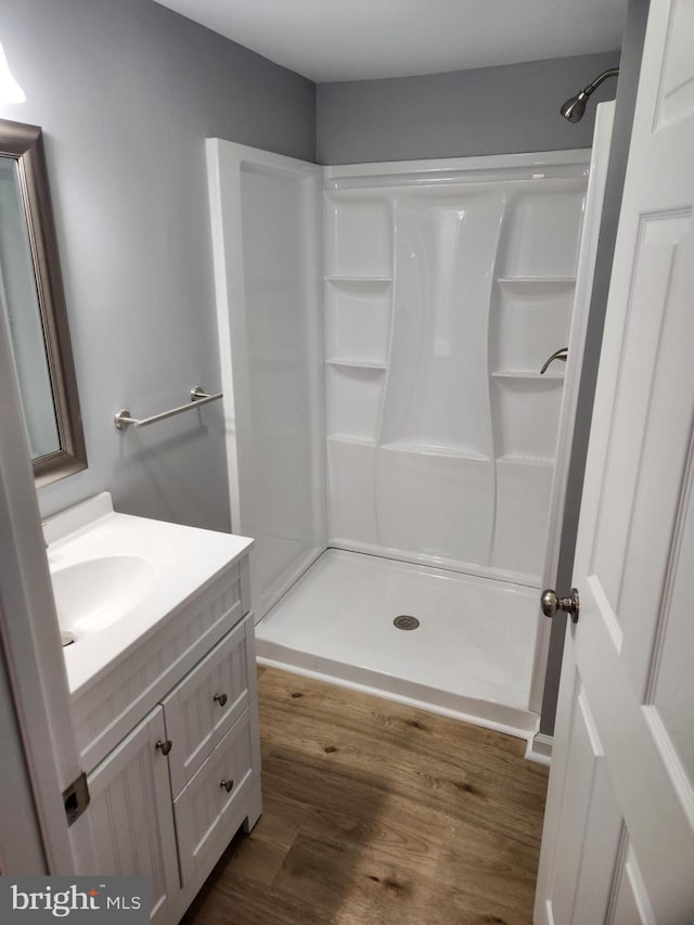 bathroom with hardwood / wood-style floors, vanity, and a shower