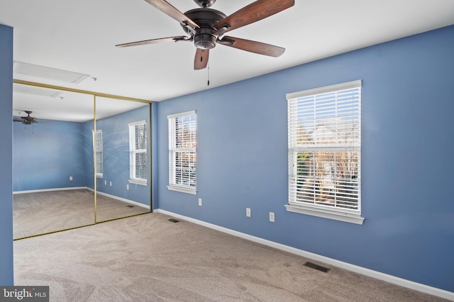 unfurnished bedroom with multiple windows, ceiling fan, a closet, and carpet